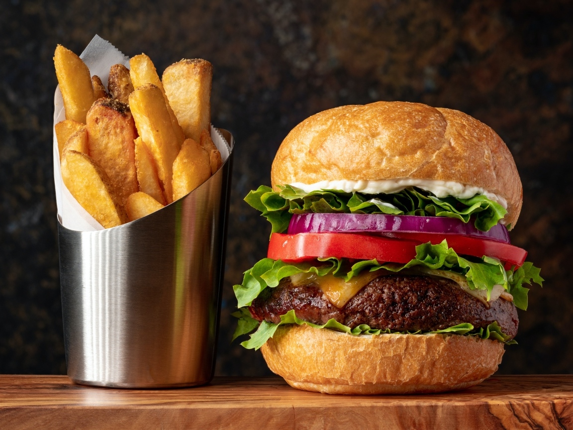 Большой гамбургер на столе с картофелем фри