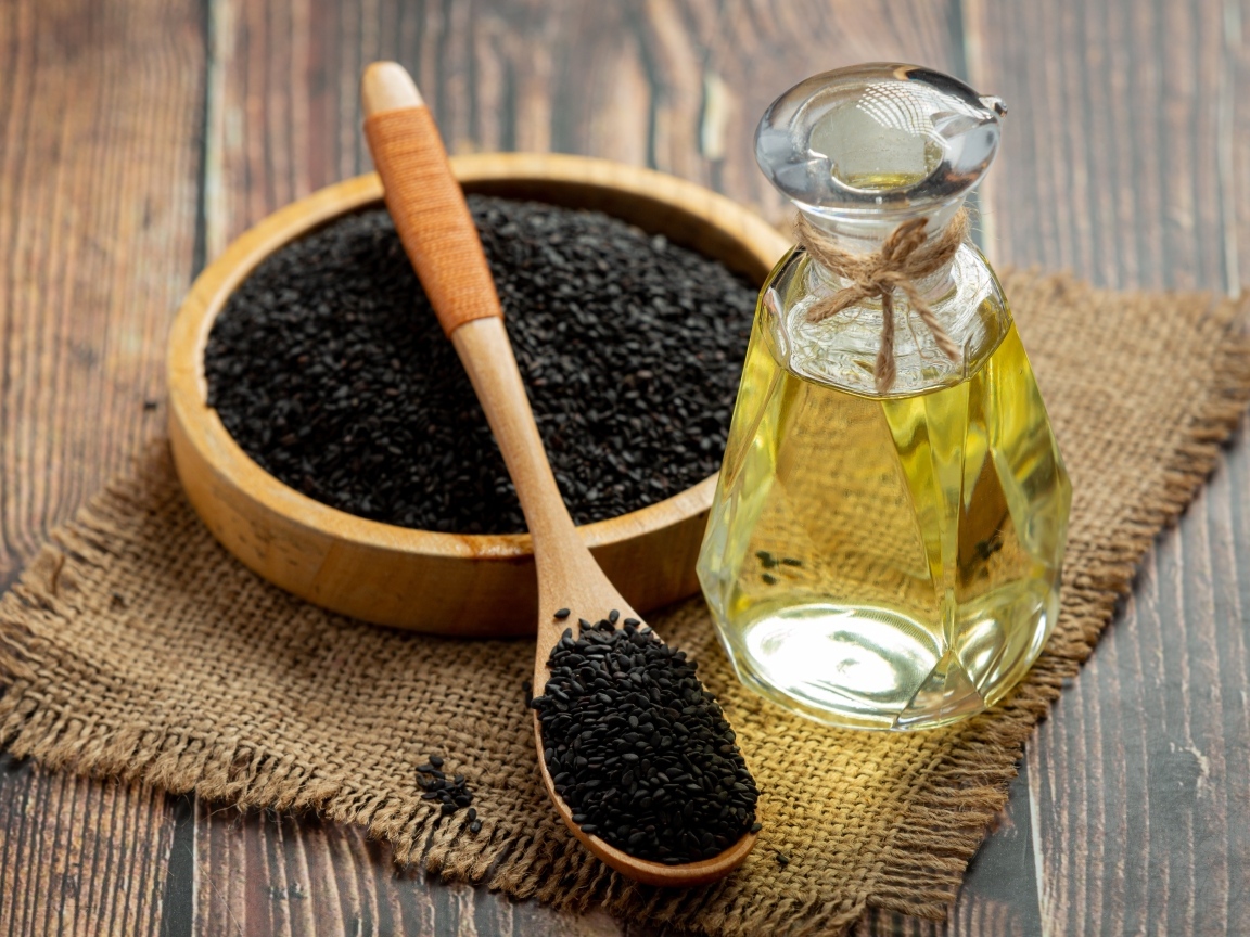 Черные семена на столе с маслом