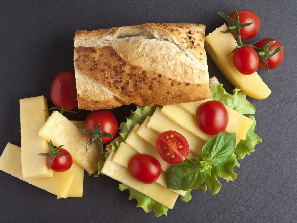 Сыр с батоном и помидорами на столе