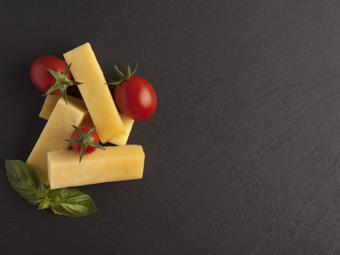 Сыр с помидорами и листьями базилика на сером столе