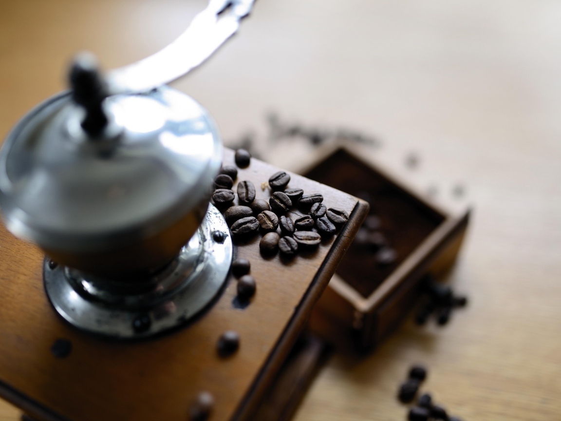 Кофемолка на столе с зернами