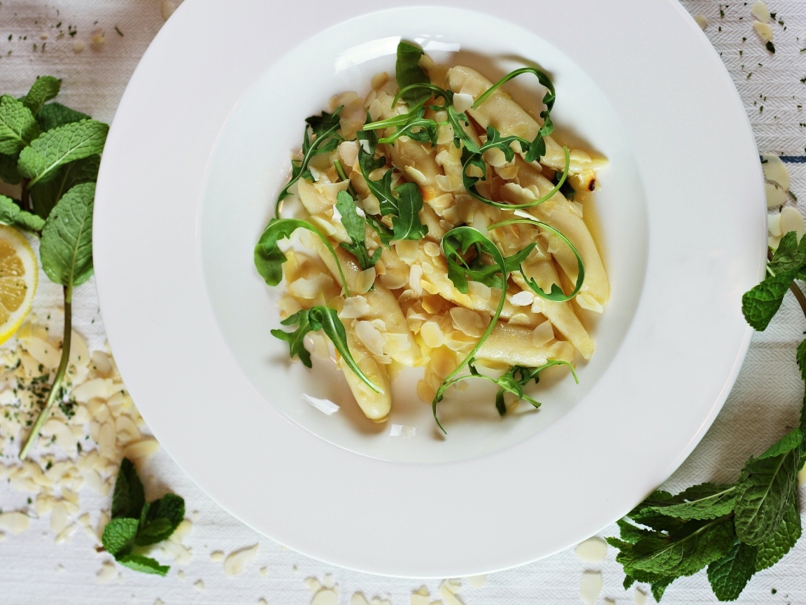 Блюдо с листьями рукколы в большой белой тарелке