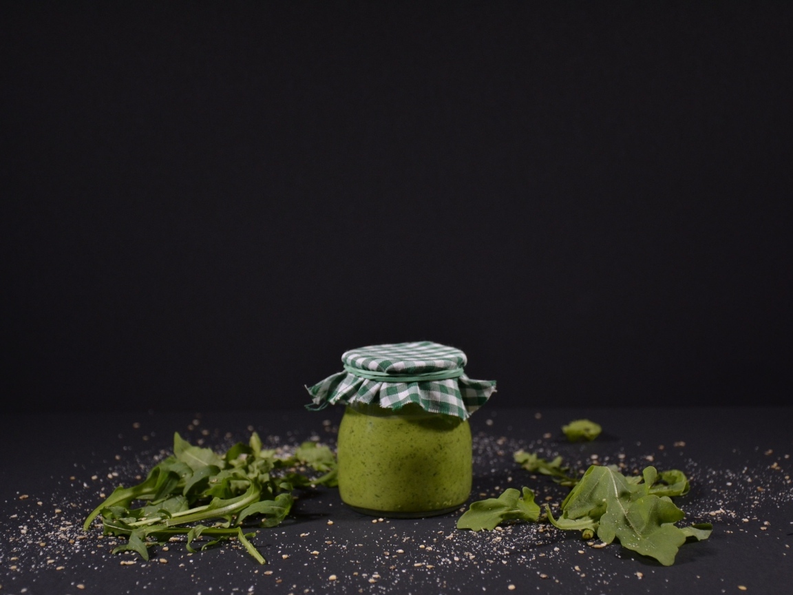 Банка соуса песто на черном фоне