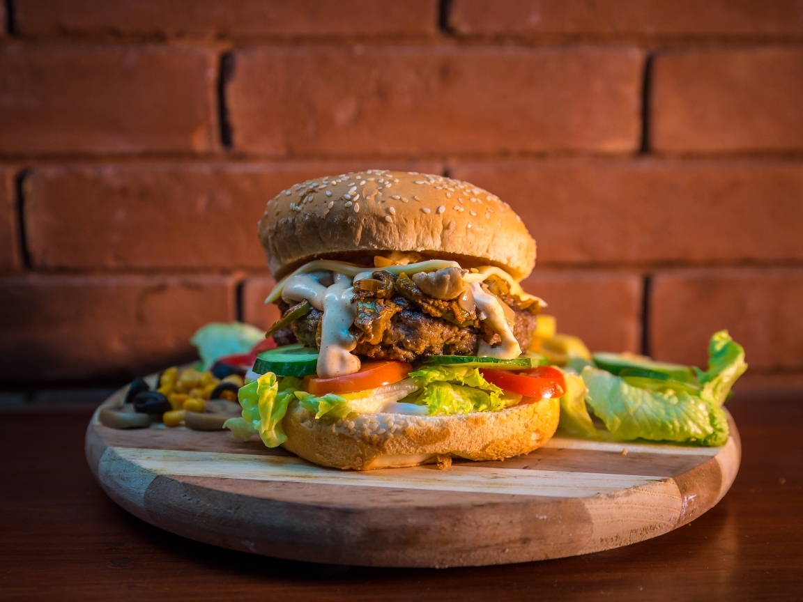 Большой аппетитный гамбургер на фоне стены