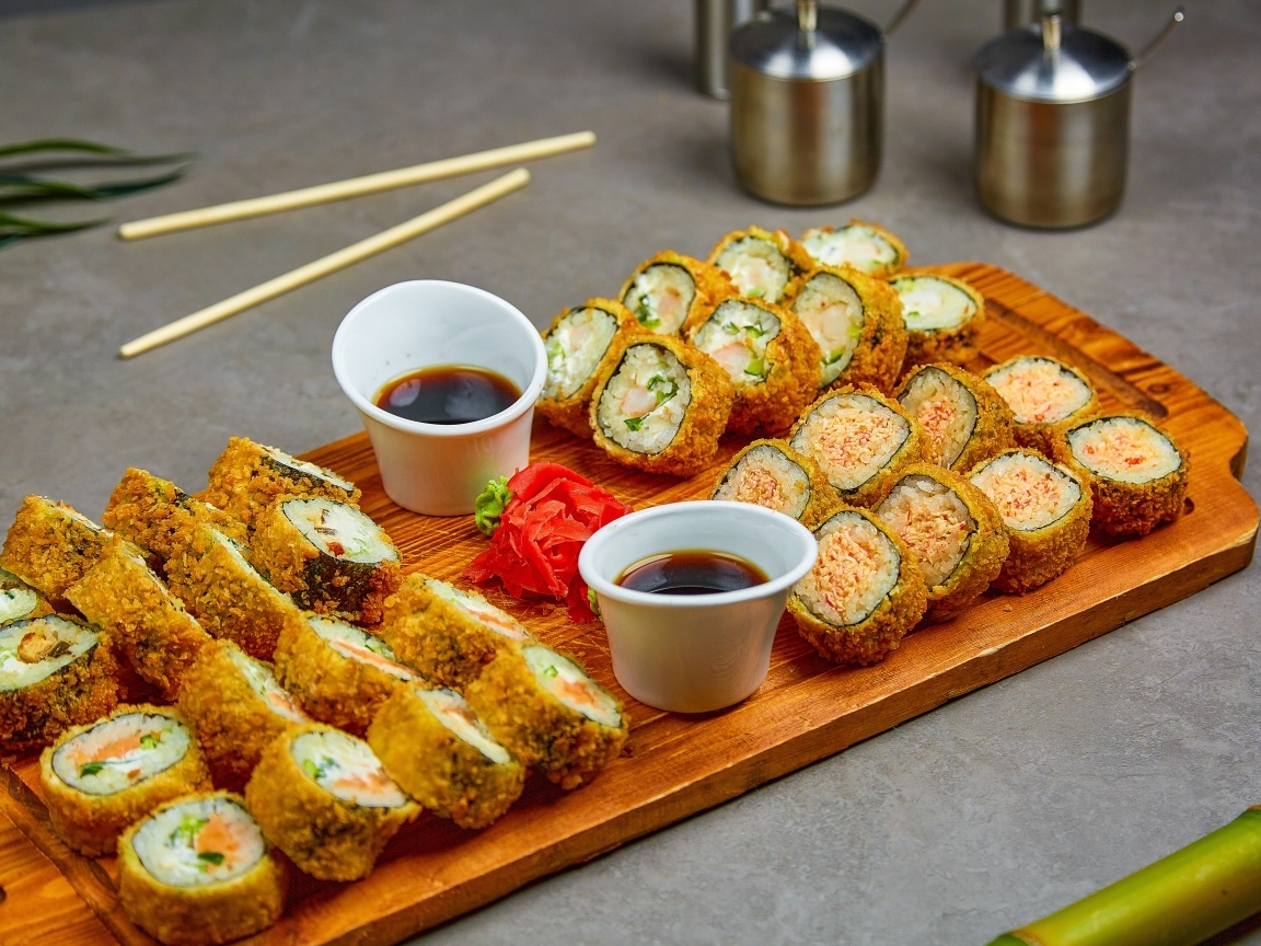 Роллы с соевым соусом на доске на столе