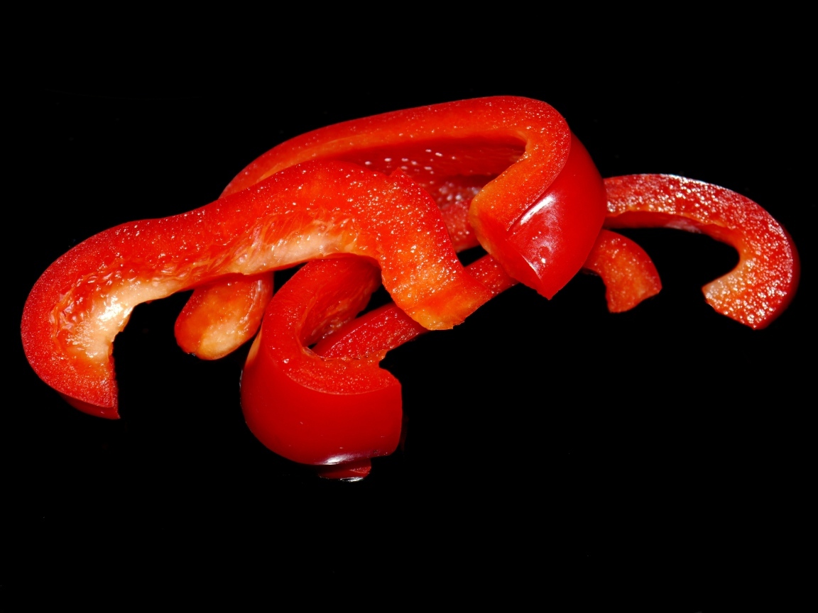 Нарезанный сладкий красный перец на черном фоне