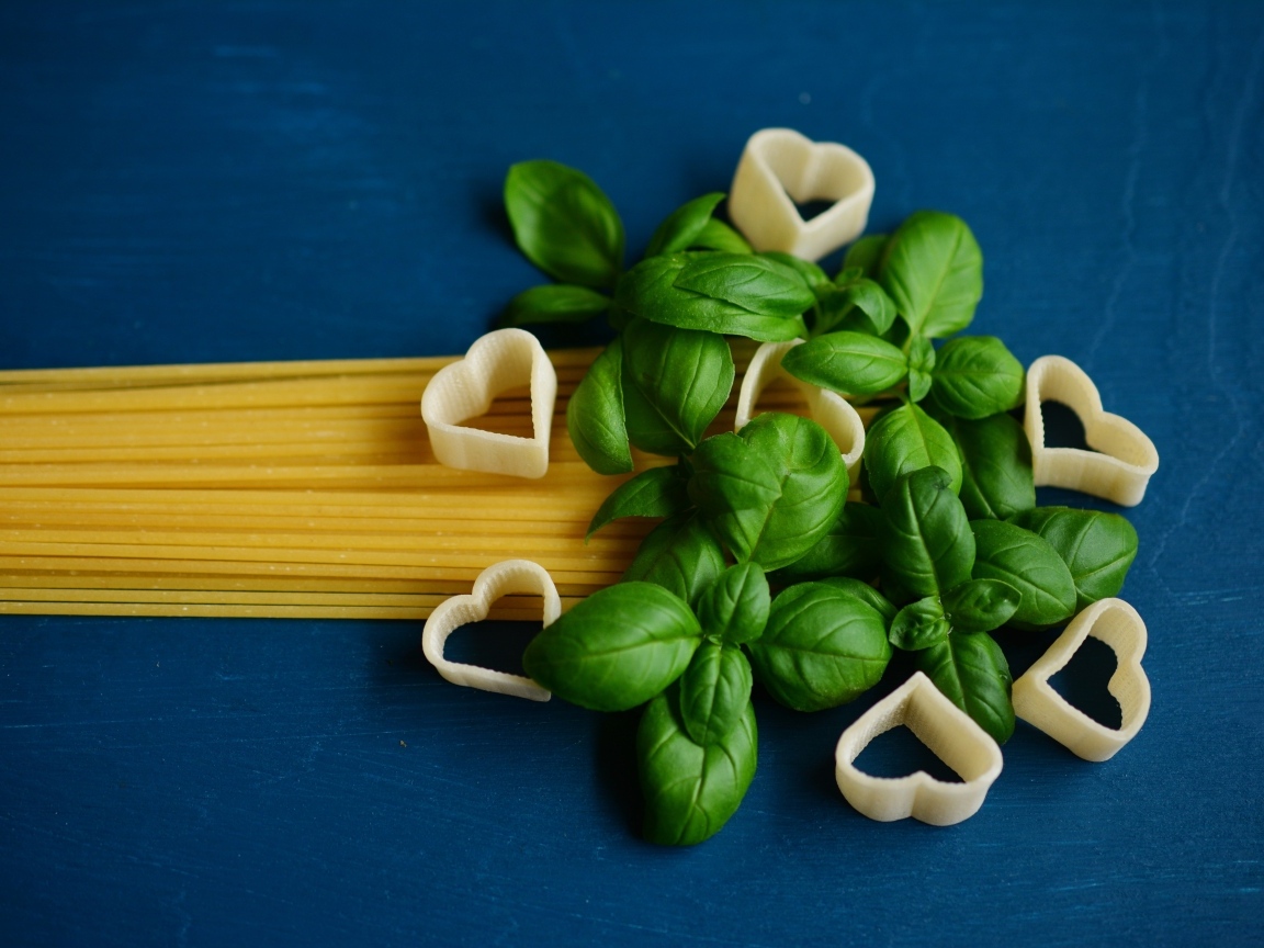 Спагетти на синем фоне с листьями базилика