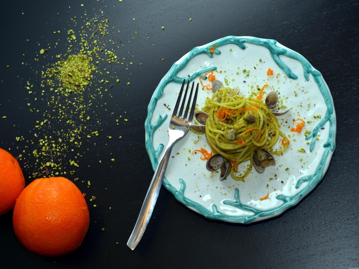 Спагетти с морепродуктами на столе с апельсинами