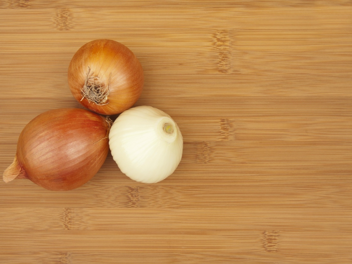 Три луковицы на деревянном столе