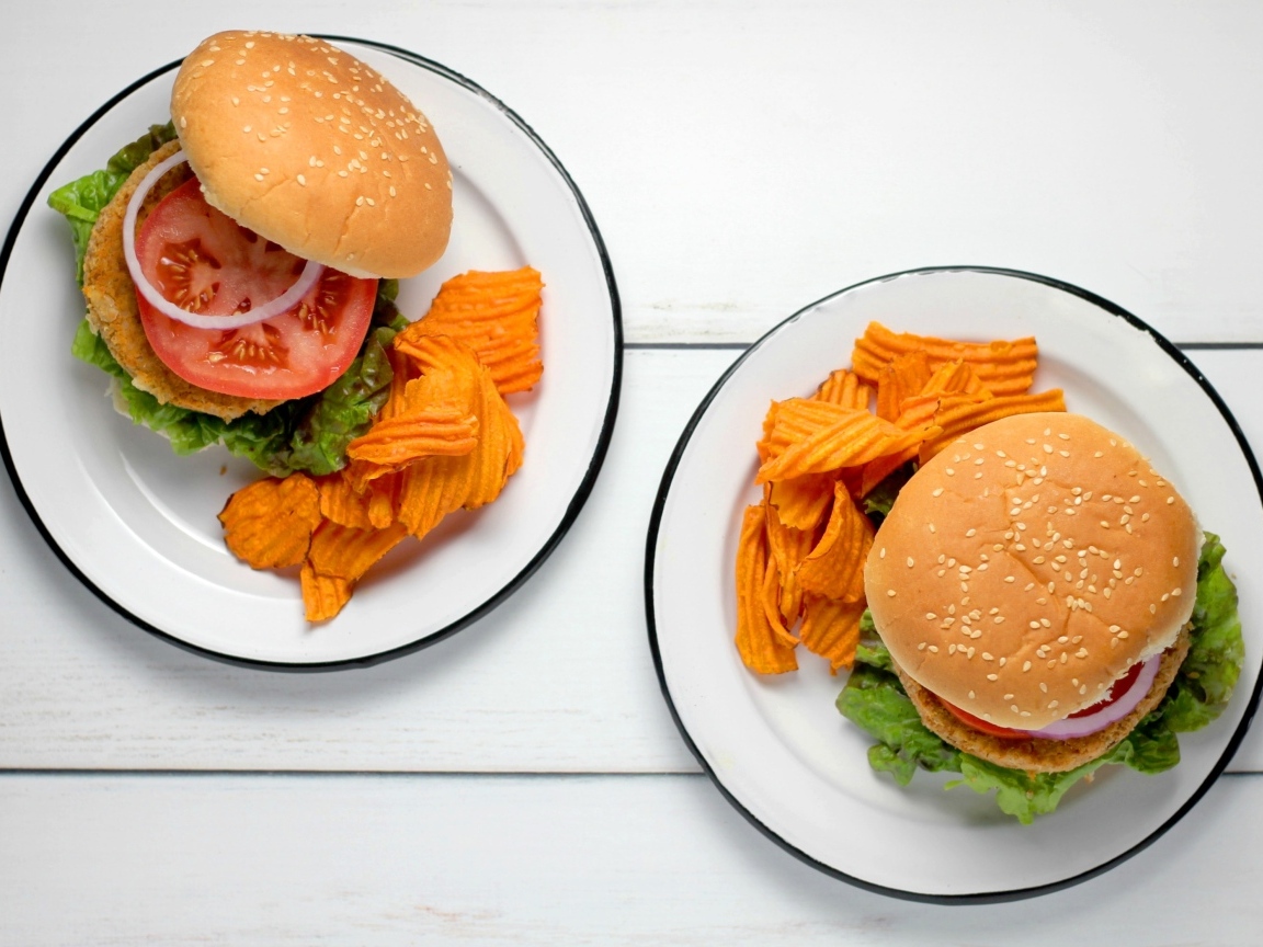 Два гамбургера на тарелке с чипсами