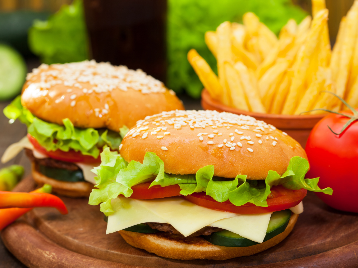 Два больших гамбургера на столе с картофелем фри