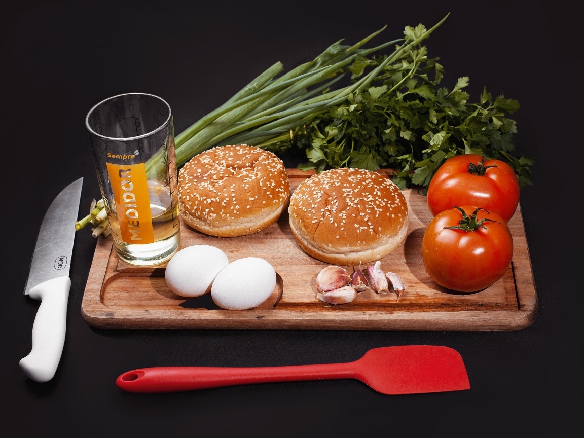 Овощи, яйца, зелень и булочки на черном фоне