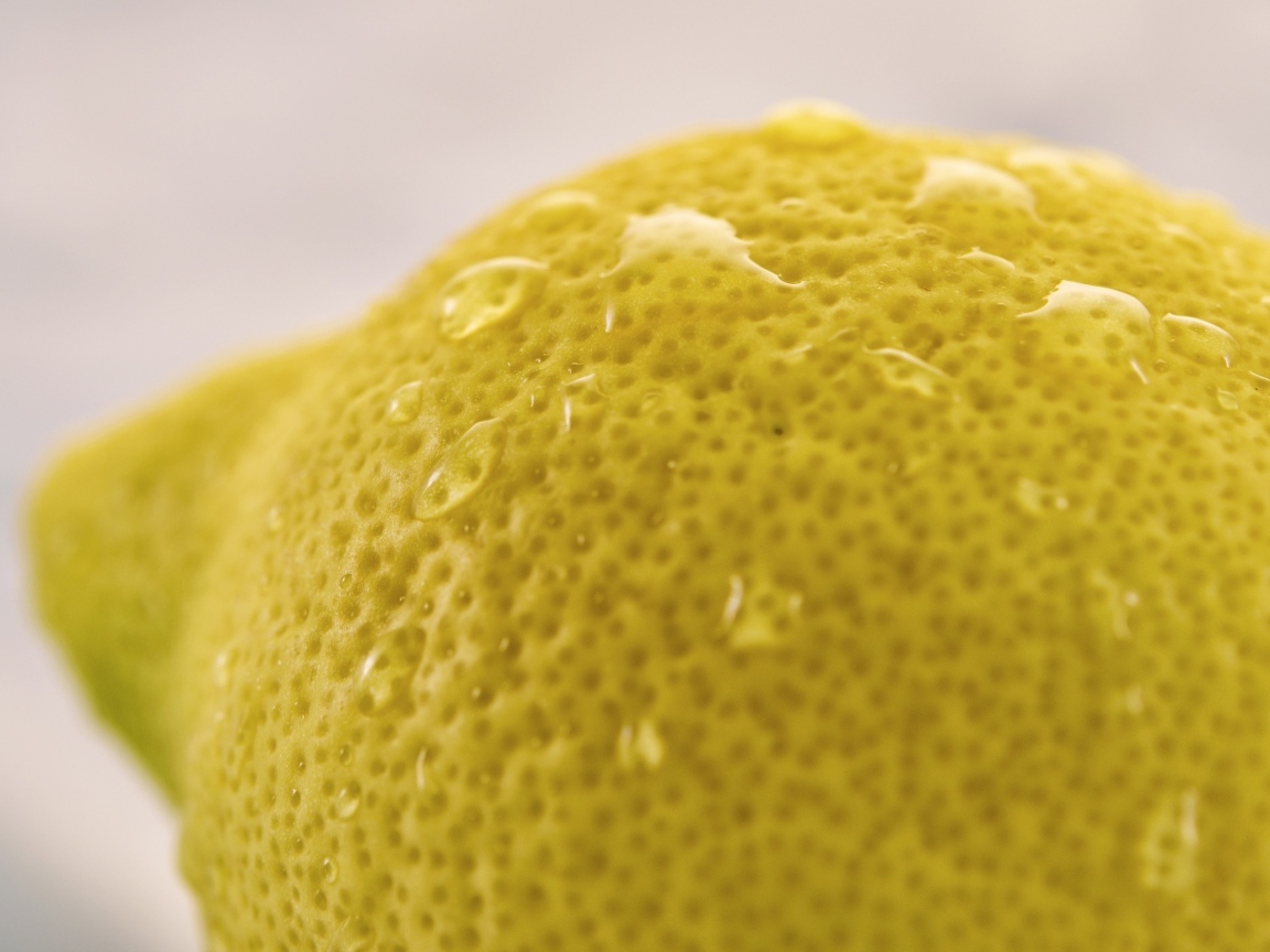 Большой желтый лимон в каплях воды крупным планом