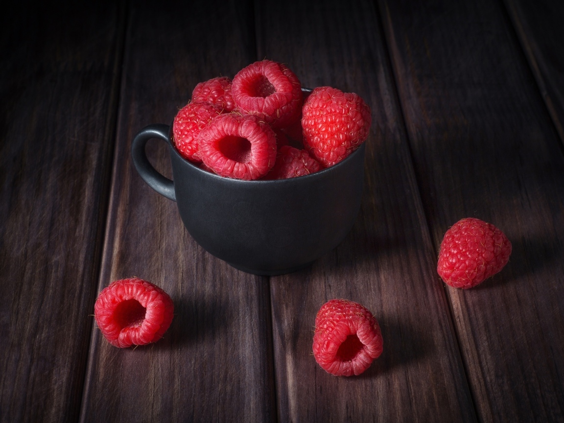 Черная чашка с красными ягодами малины