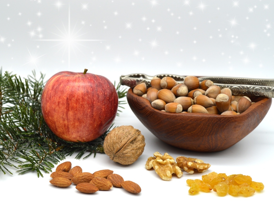 Орехи с яблоком и еловой веткой на столе
