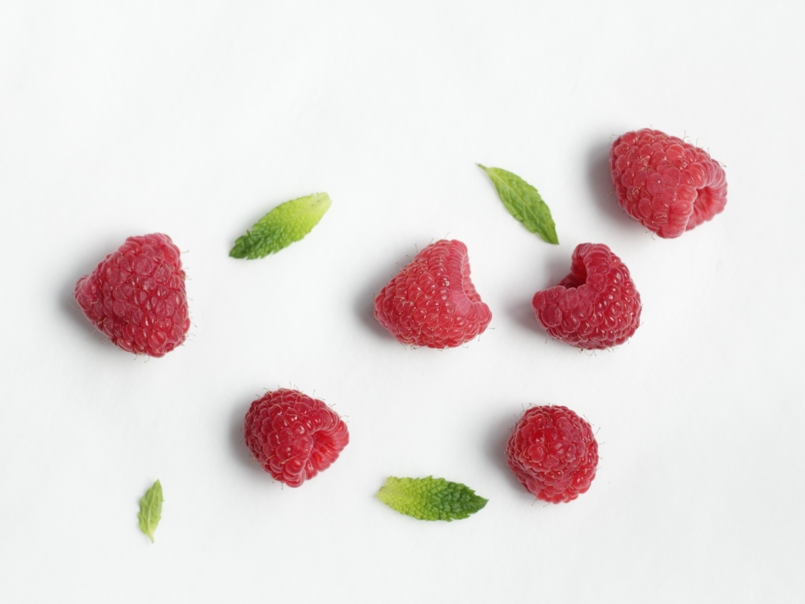 Красная малина с зелеными листьями на белом фоне