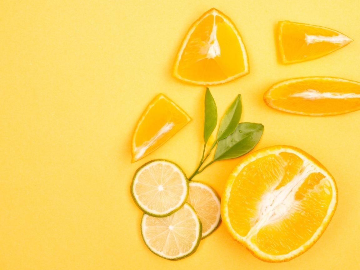 Нарезанные плоды апельсина и лайма на желтом фоне