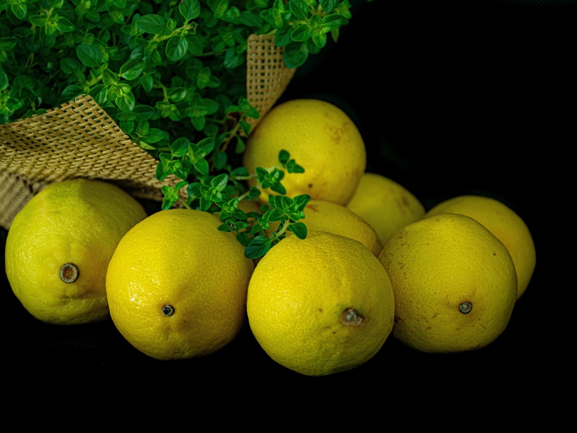 Желтые лимоны с зеленью на столе