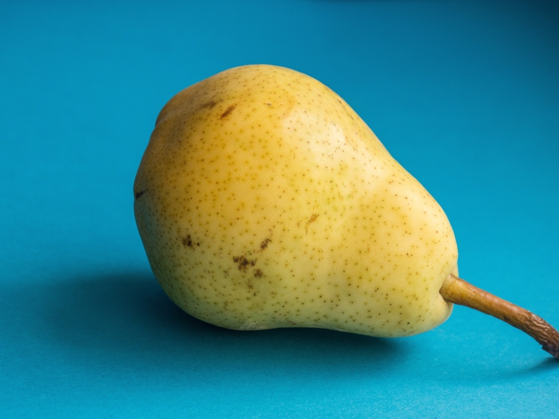 Желтая груша на голубом фоне