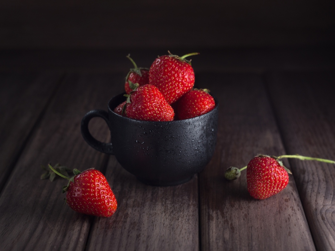 Черная чашка с красными ягодами клубники