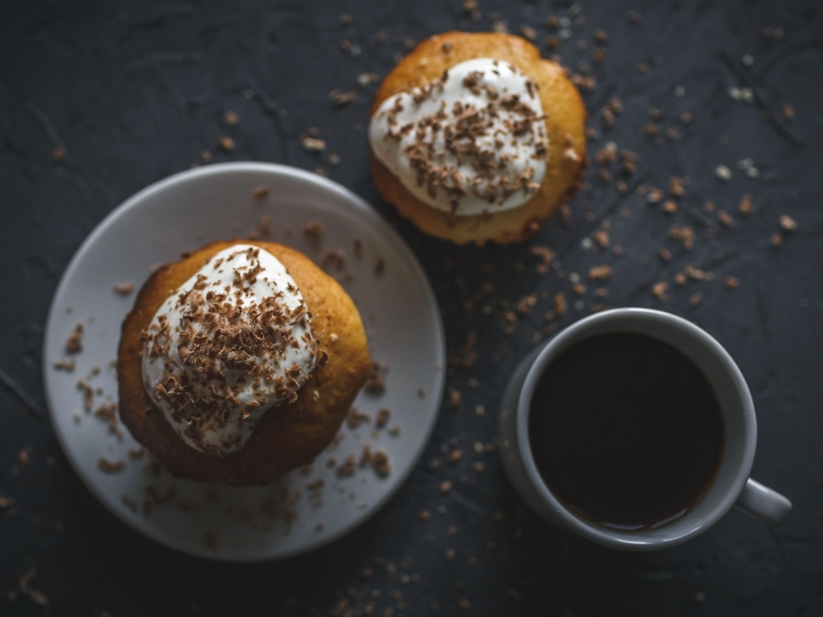 Пирожное в тертым шоколадом на столе с чашкой кофе