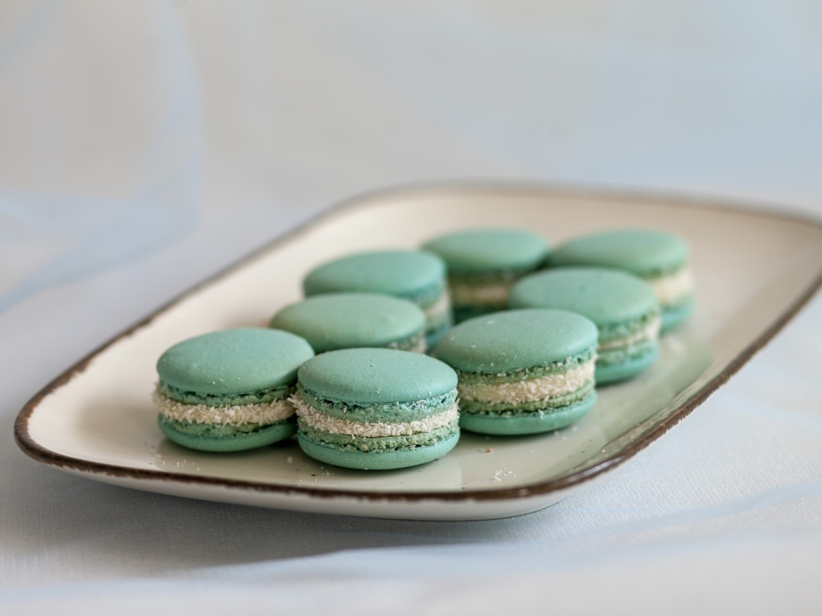 Зеленый десерт макаронс на большой тарелке на столе