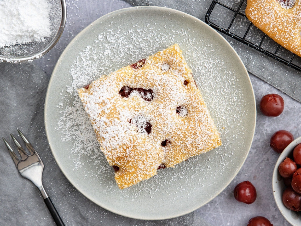 Кусок вишневого пирога на тарелке с сахарной пудрой