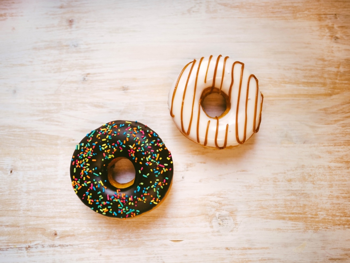 Два пончика в глазури на деревянном столе