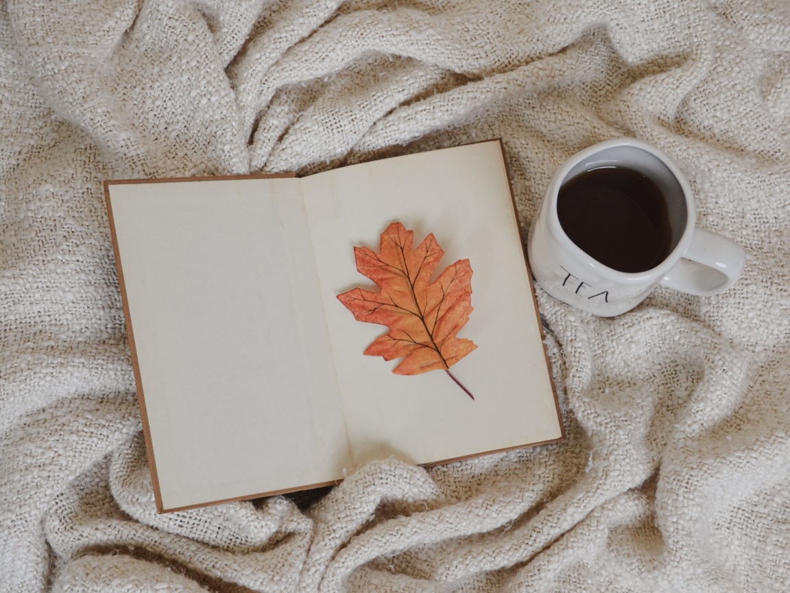 Книга, желтый лист и чашка кофе с пледом