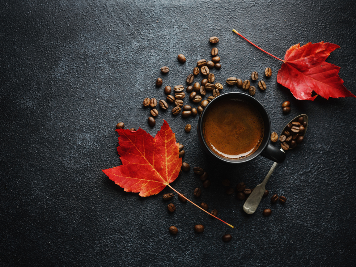 Чашка кофе на столе с зернами и желтыми листьями