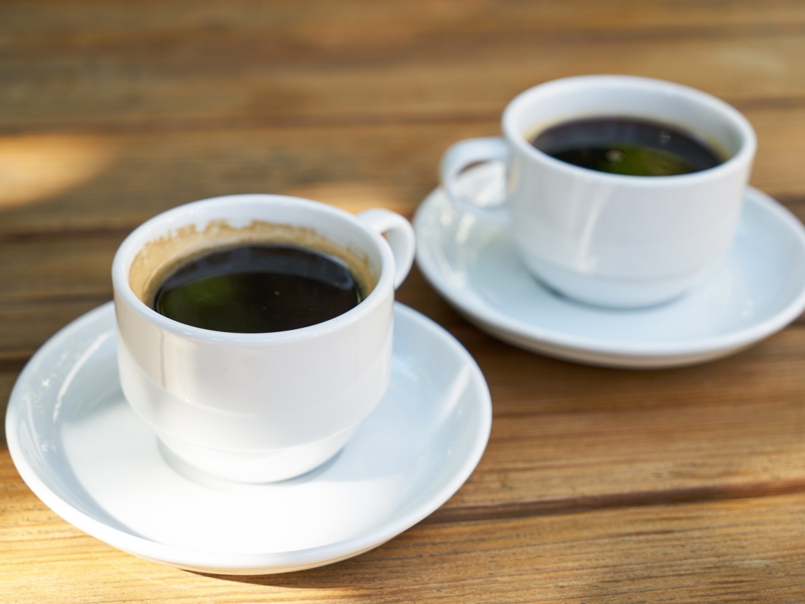 Две белые чашки кофе на столе 