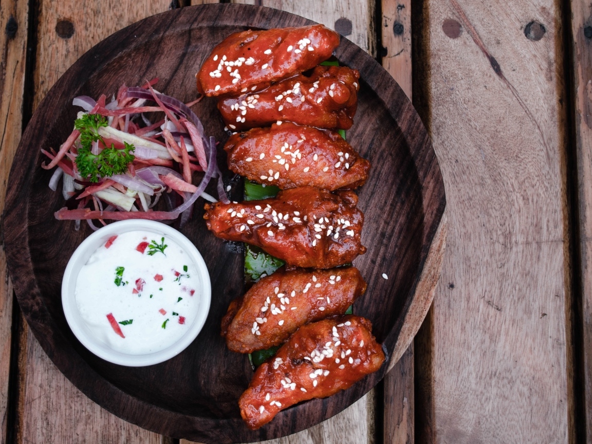 Запеченные куриные крылышки с соусом на тарелке