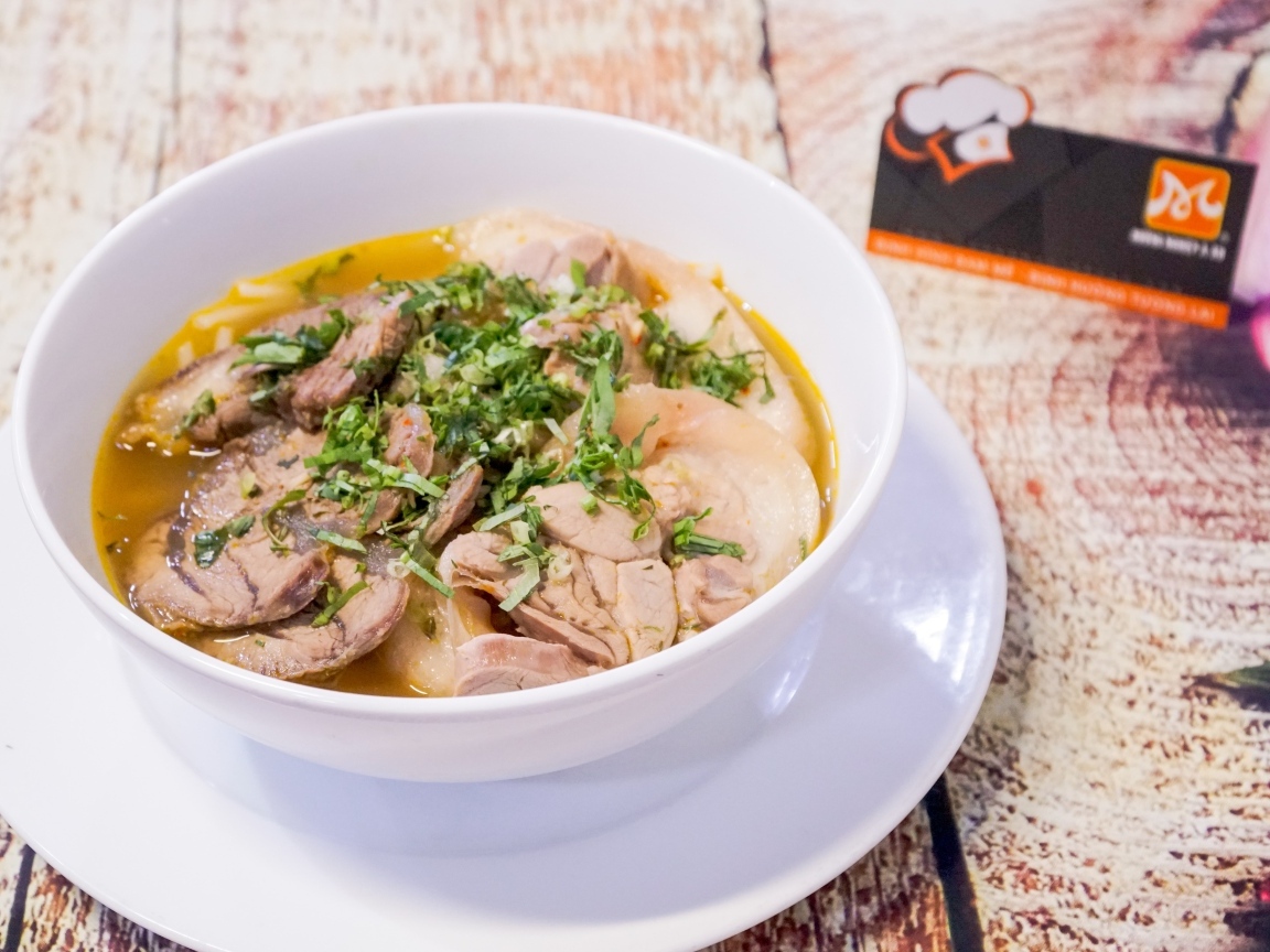 Broth with meat in a white plate on the table