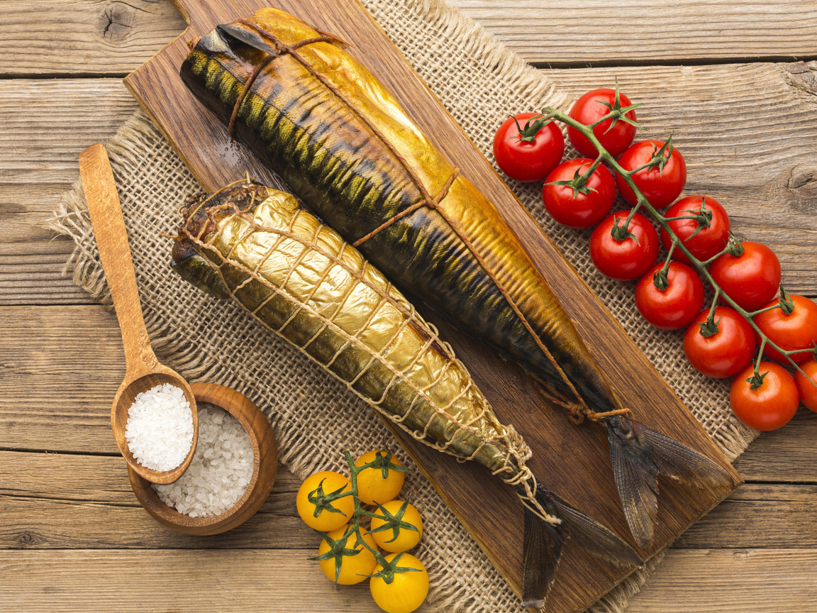 Две копченые скумбрии на столе с помидорами