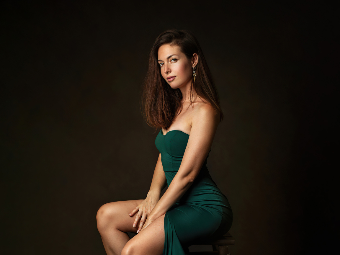 Девушка в зеленом платье сидит на стуле