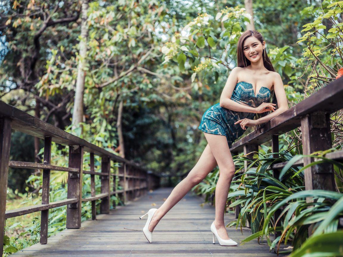 Девушка азиатка в коротком платье у перил на мосту