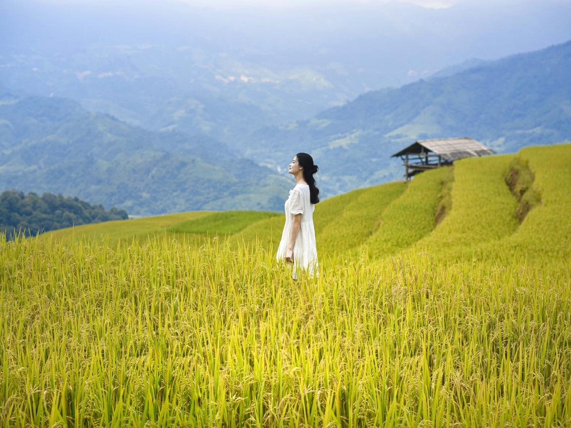 Девушка азиатка в белом платье дышит горным воздухом