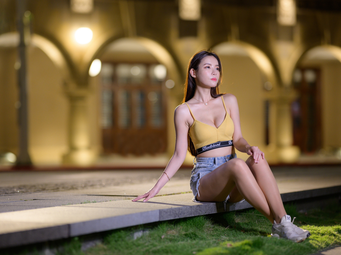 Девушка азиатка сидит на бетонной плите у дома