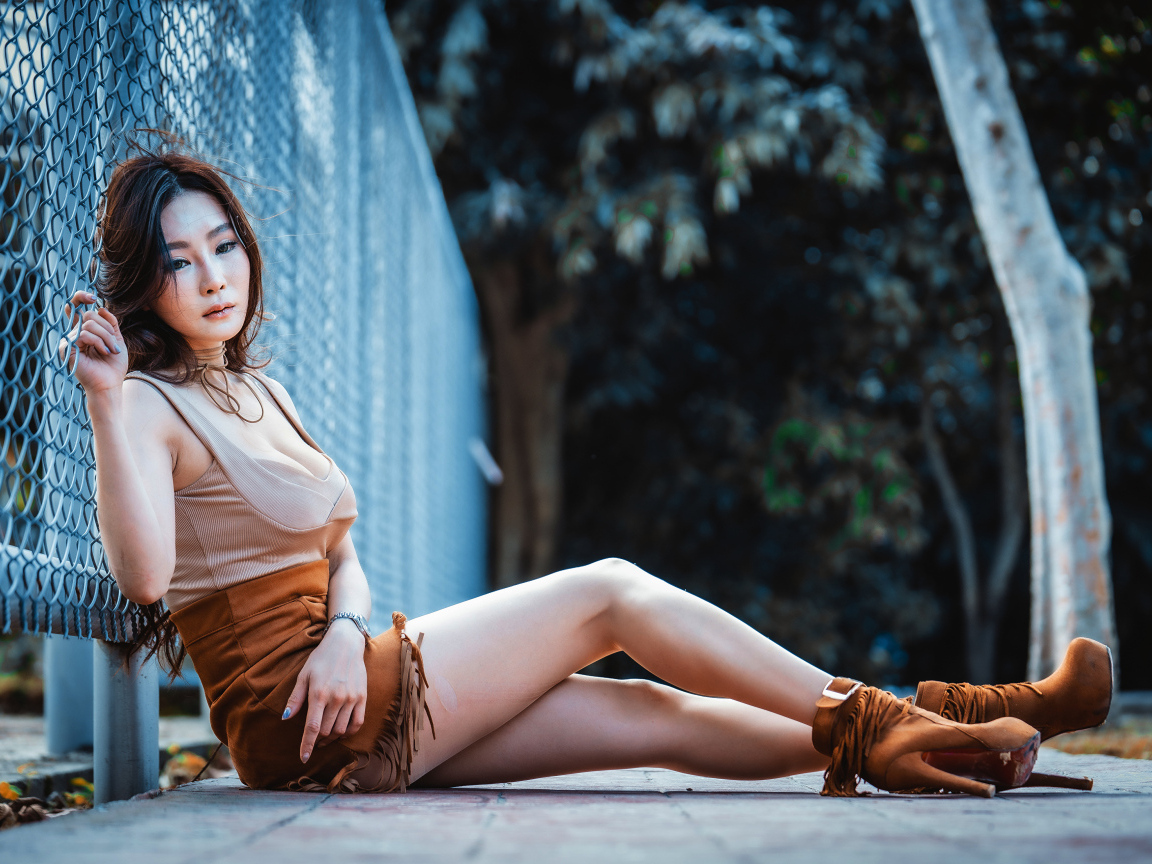 Девушка азиатка сидит на земле у сетки