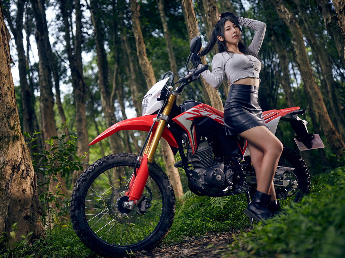 Девушка азиатка с мотоциклом в лесу