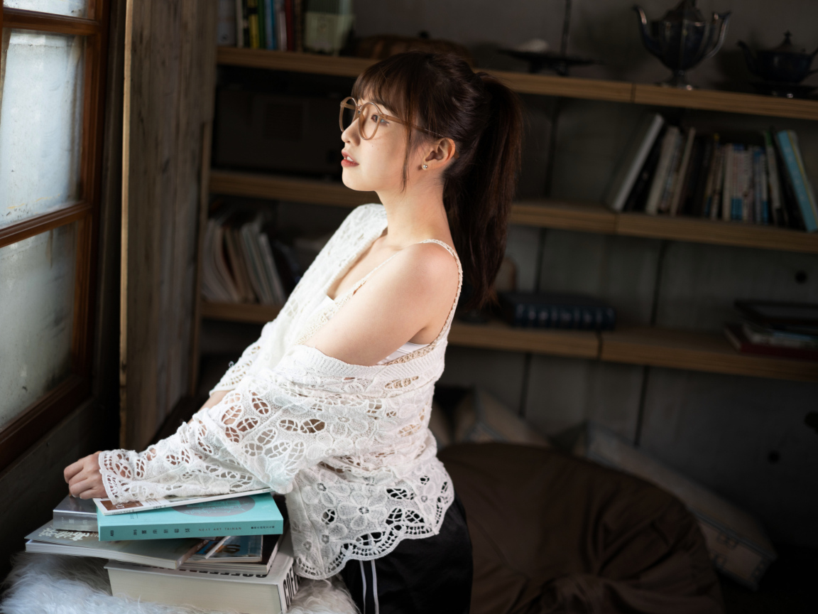 Девушка азиатка с книгами у окна