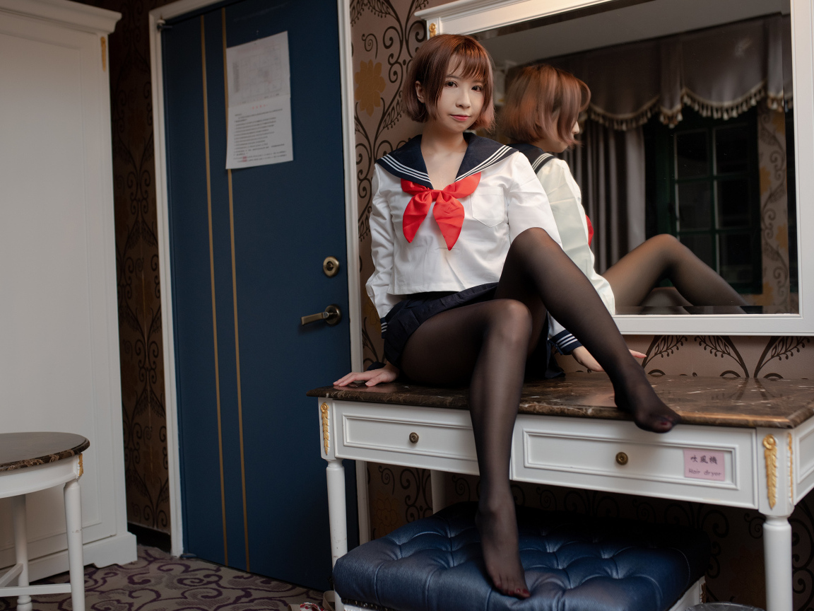 Азиатка в форме сидит на столе