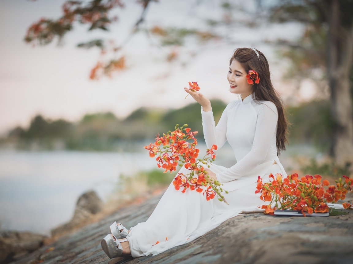 Красивая девушка азиатка в белом платье с цветами в руке