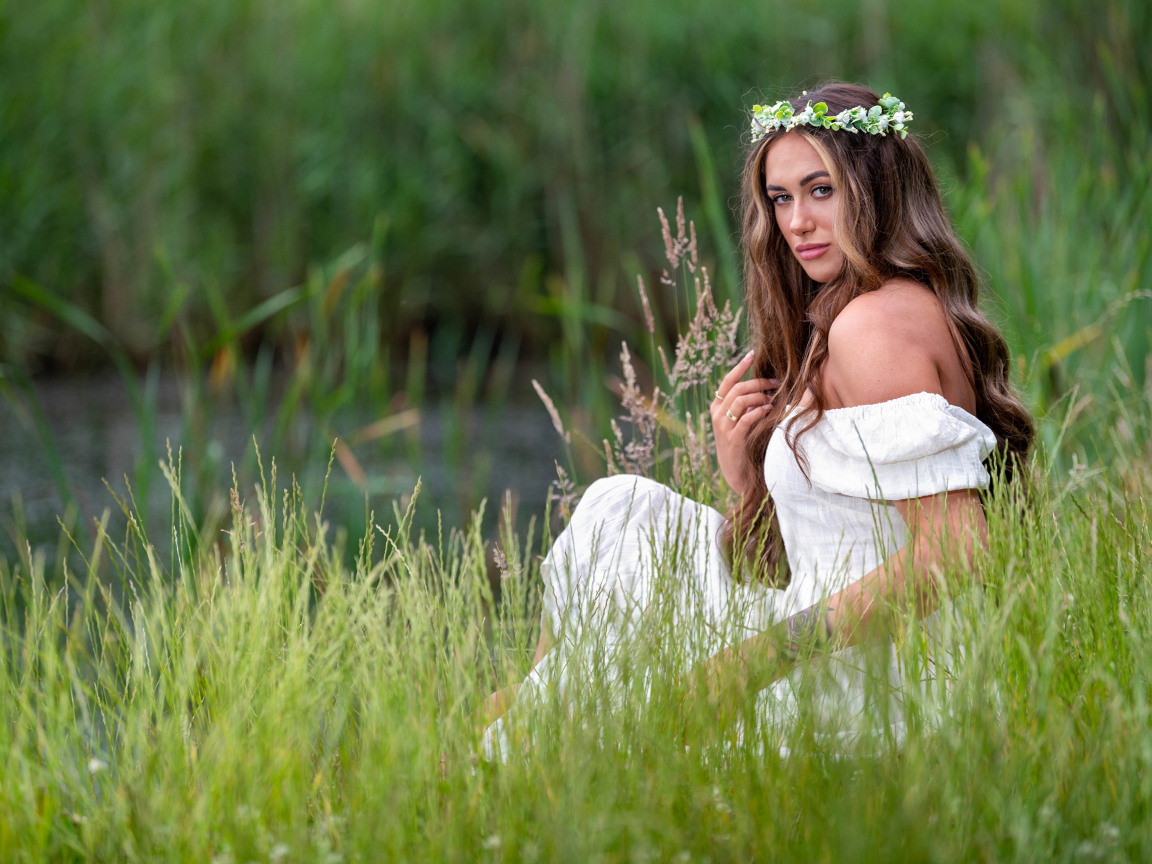 Красивая девушка в белом платье с венком на голове у пруда 