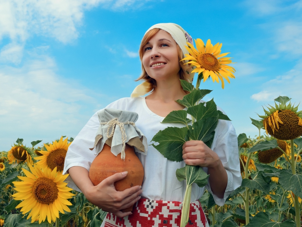 Красивая девушка с кувшином на поле с подсолнухами