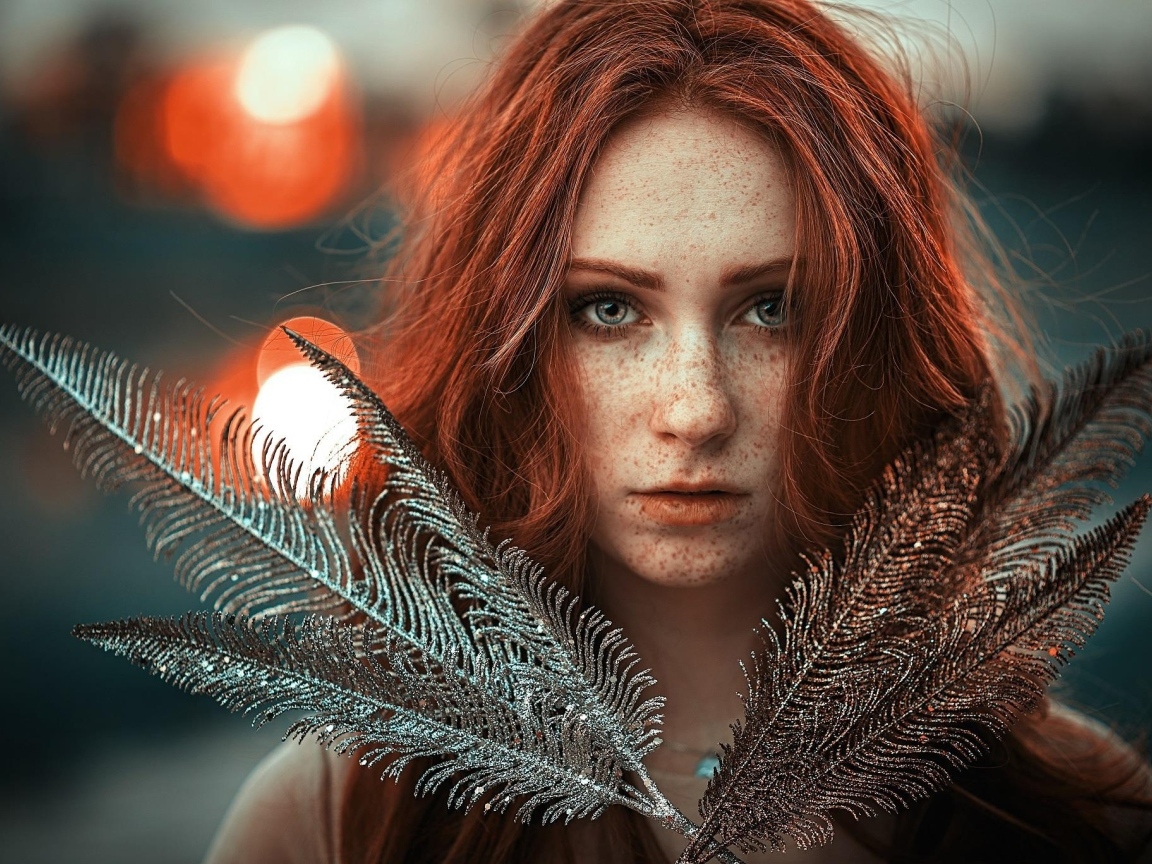 Яркая рыжеволосая девушка с перьями в руках