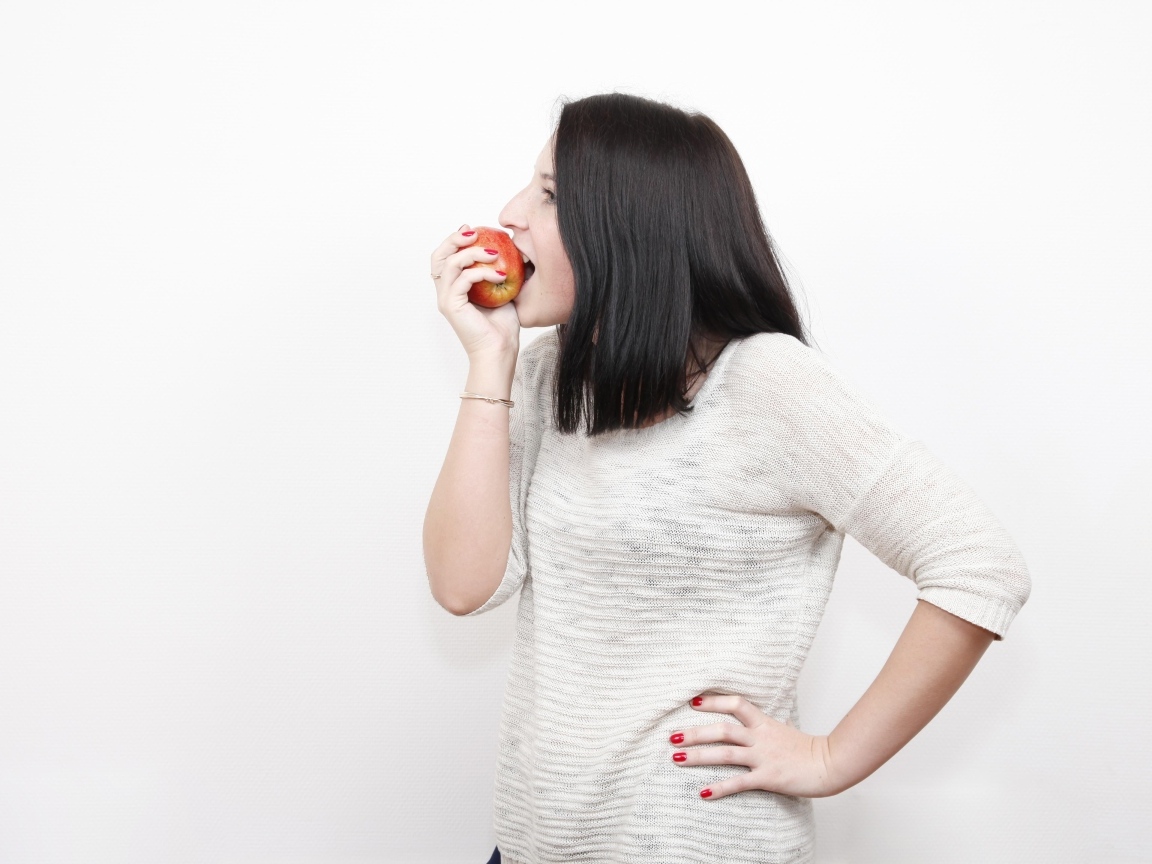 Девушка кусает красное яблоко 