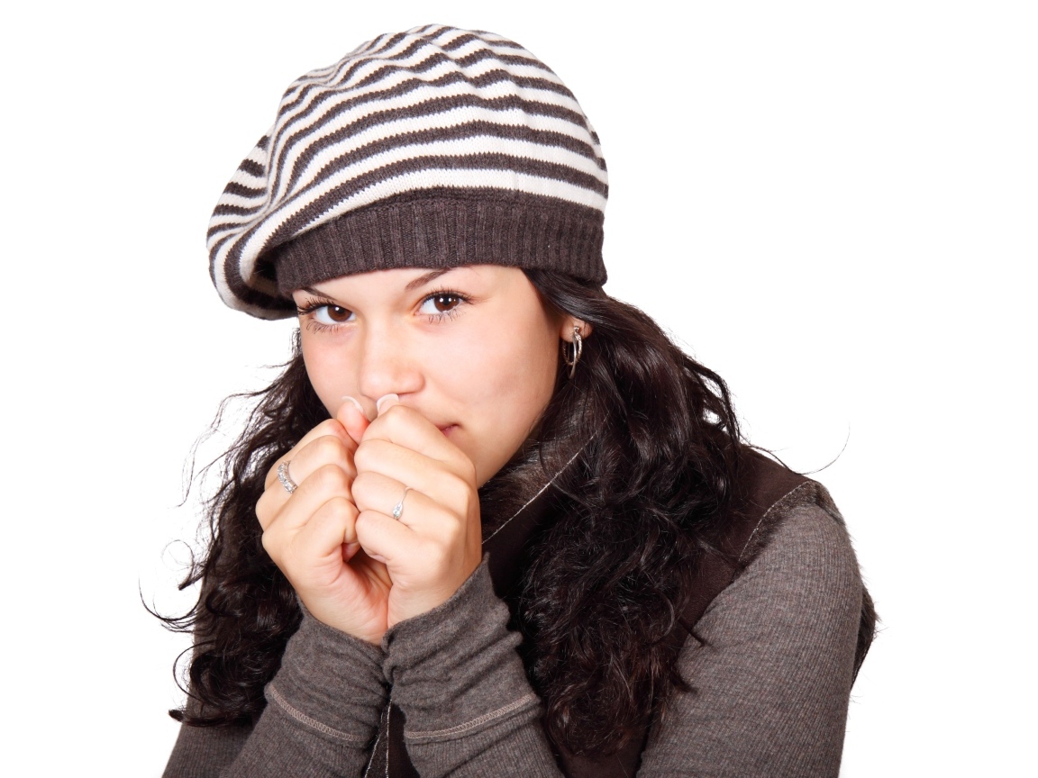 Девушка в теплой полосатой шапке на белом фоне
