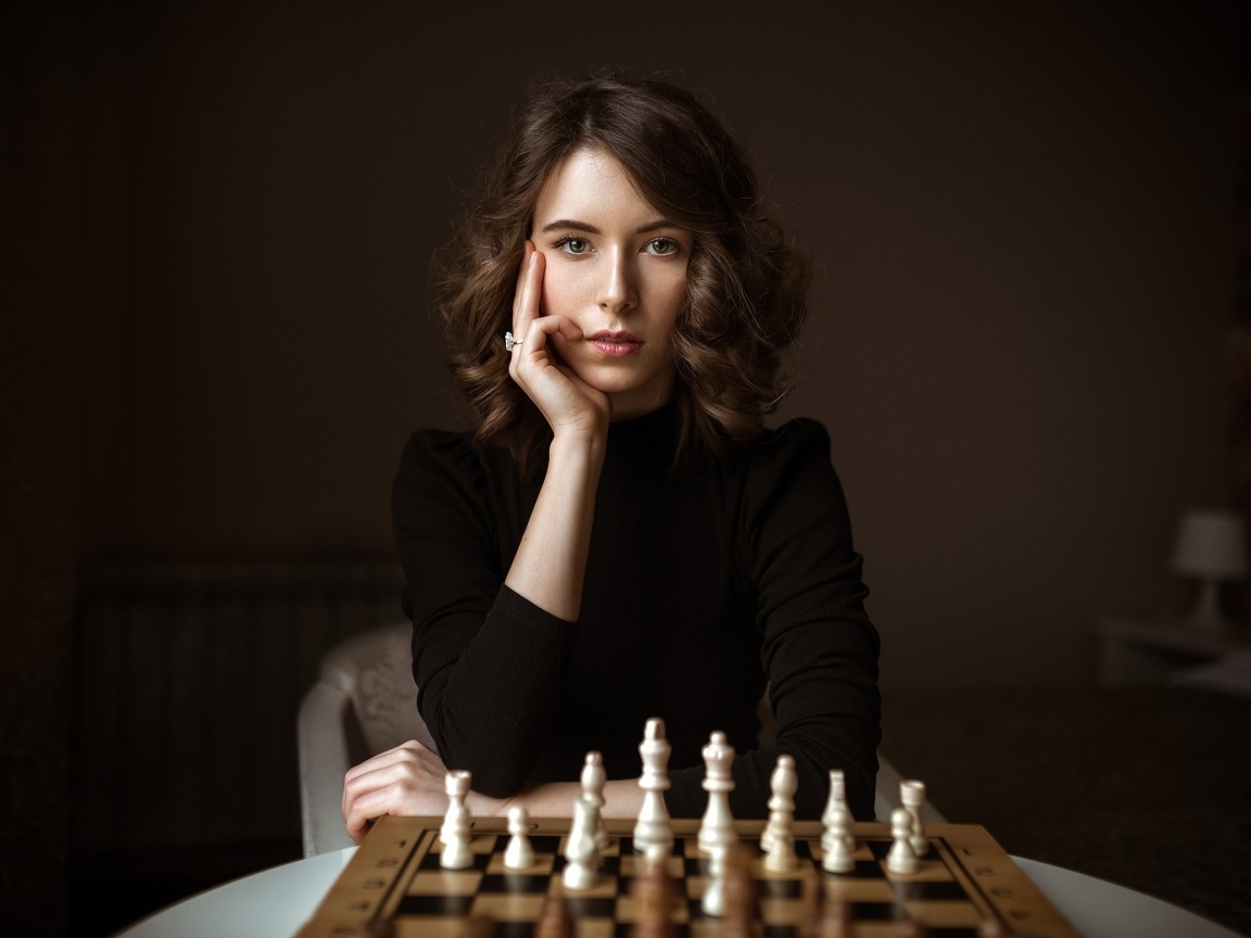 Умная молодая девушка играет в шахматы