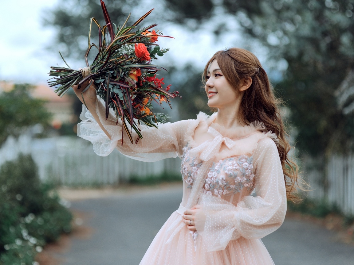 Улыбающаяся девушка азиатка в розовом платье с букетом